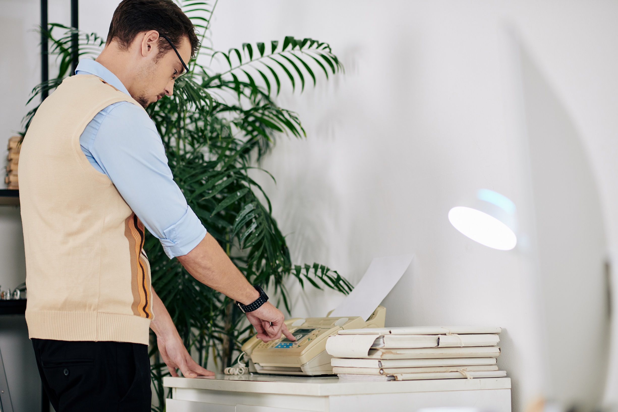 Young businessman is receiving fax in office.