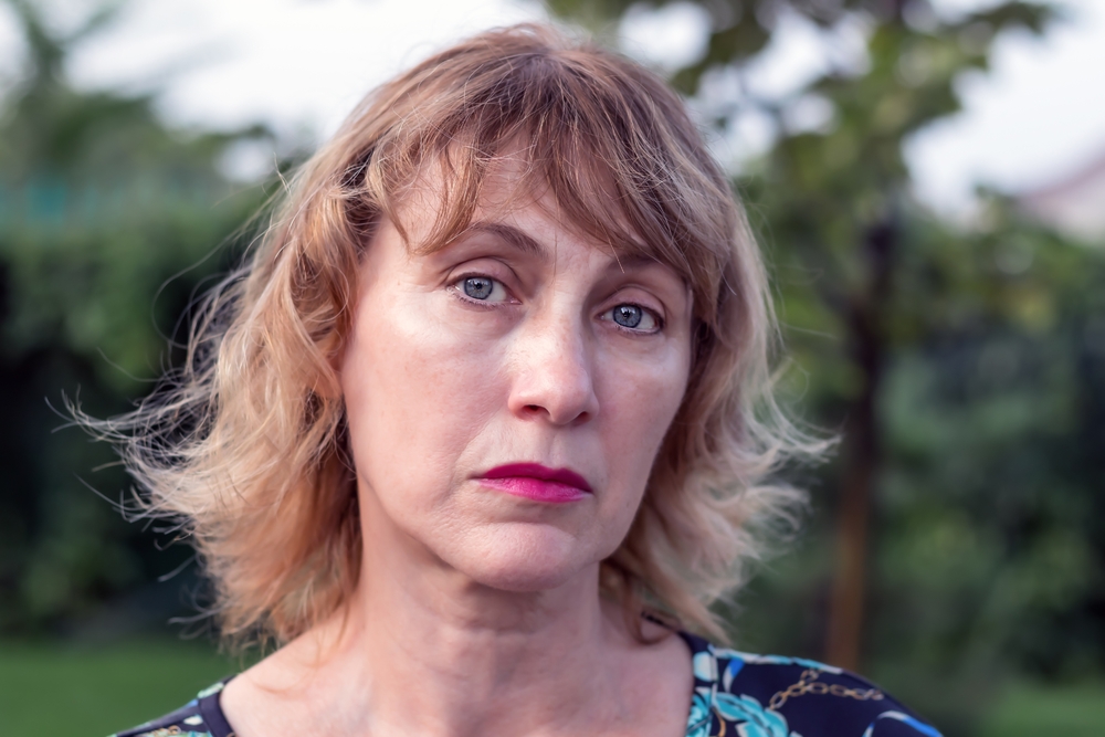 portrait of an unhappy woman of middle age 50-55 years old with blond hair