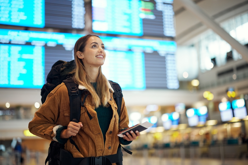excited woman with passport at airport having  ticket and documents for immigration