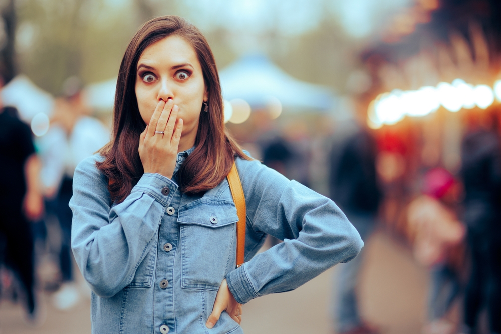 Woman feeling Sick Covering her Mouth at Local Funfair in denim shirt