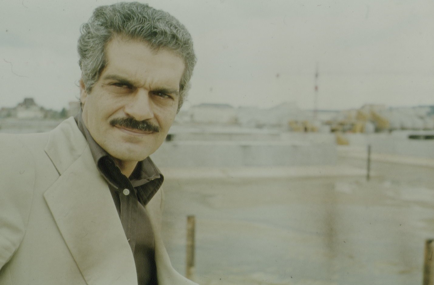 Omar Sharif in gray suit looking at camera