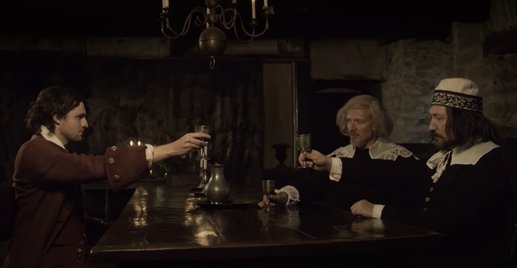Screenshot : Three man seating on theScreenshot : Three man are seating on the table and making a toast - from The Stuarts: A Bloody Reign (2018) table are talking and making a toast inside - from The Stuarts: A Bloody Reign (2018)