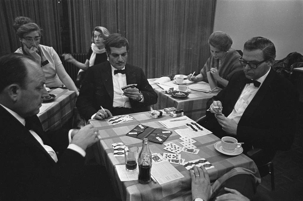 Bridge demonstration by Omar Sharif sitting at table in suit