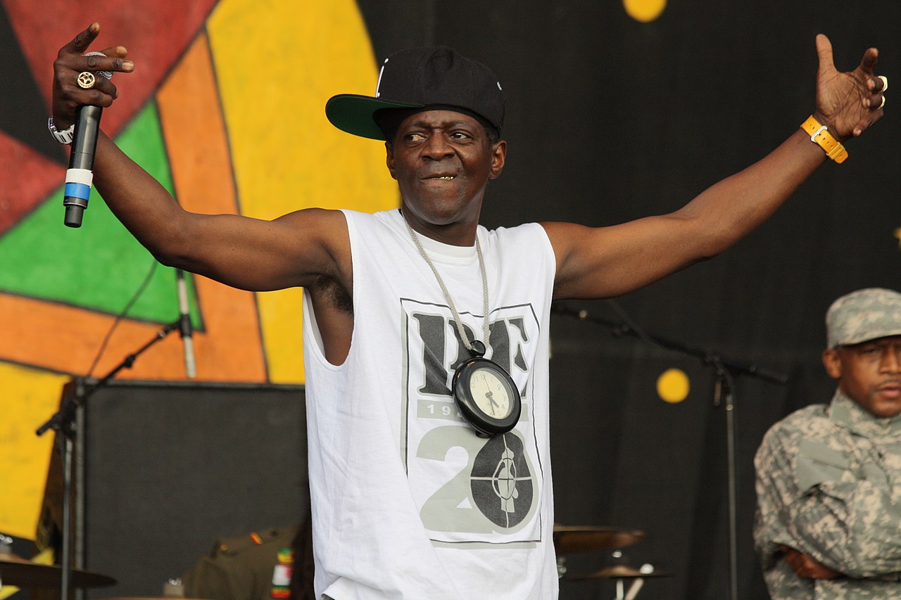 Flavor Flav (Public Enemy) wearing white shirt ,black hat and big clock on neck - 2014
