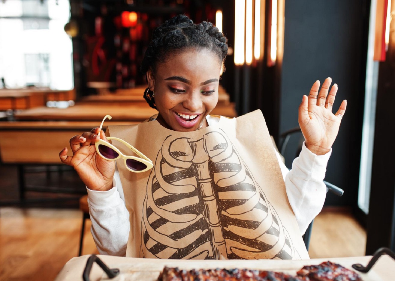 Young black woman is happy looking at food at restaurant.