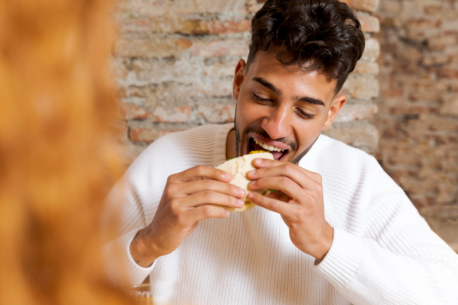 Man with beard is eating food at restaurant table.