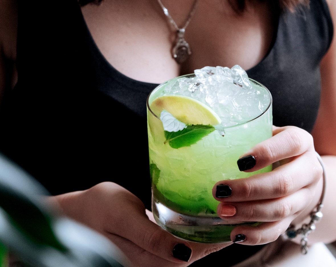 Girl holds a glass of margarita with lemon.