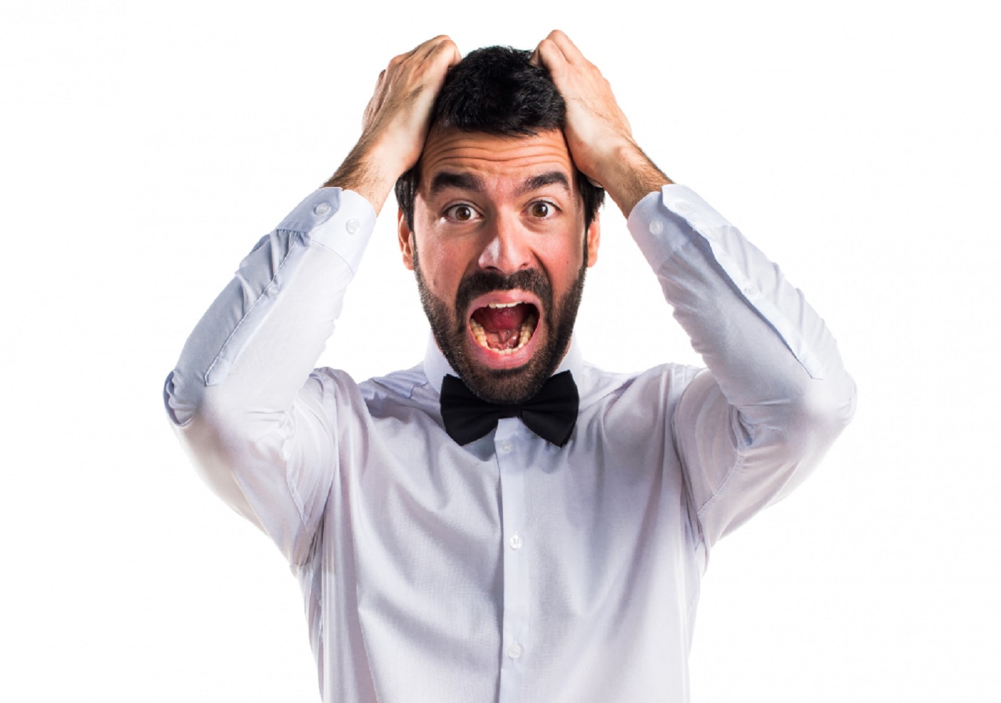 Man wearing white shirt and black bow tie holding his head and looking shocked.