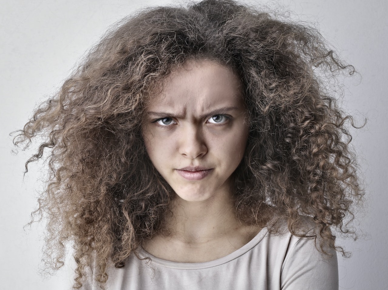 Young woman with messy hair looking angry at camera.