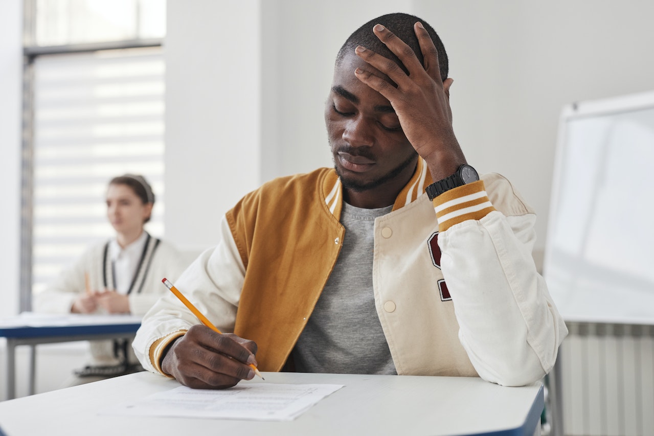 Young man is taking an exam,looking down.