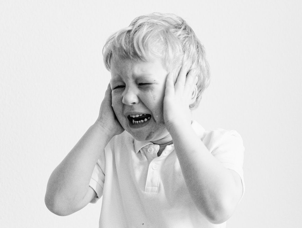 Grayscale photo of boy crying.