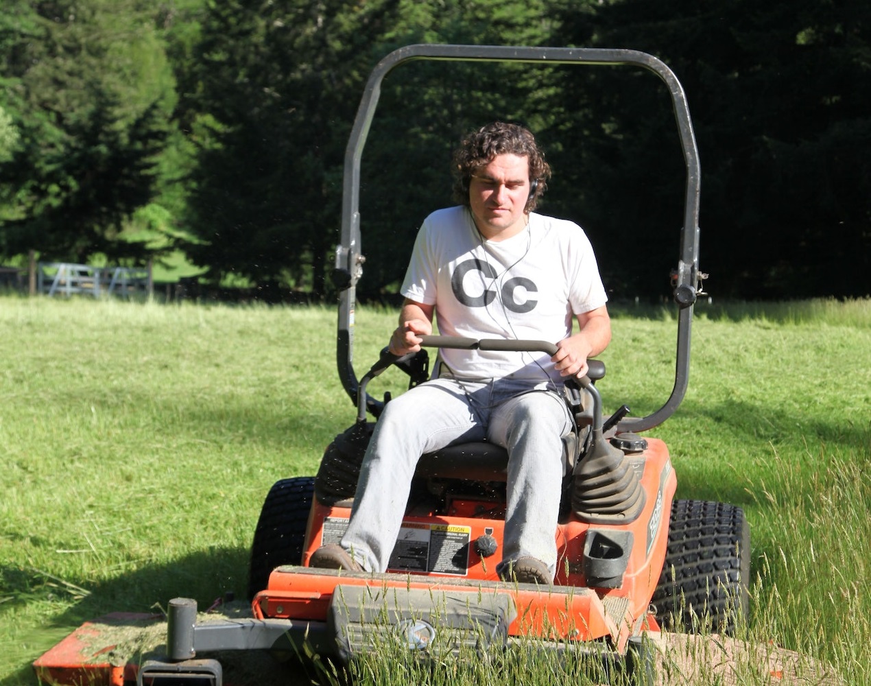 Man is driving a riding mower in the grass.