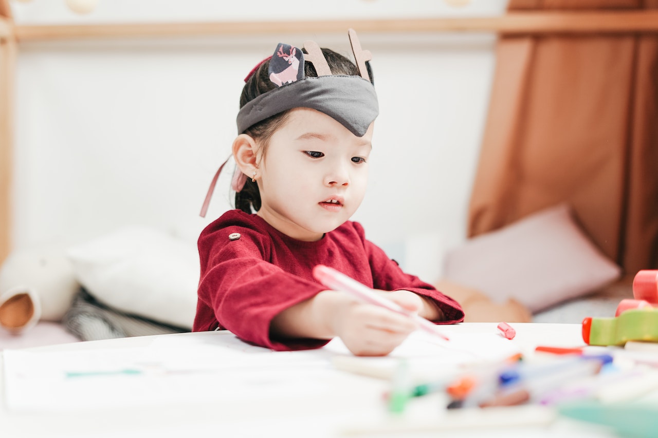 Kid wearing red shirt is playing with toys in kindergarten