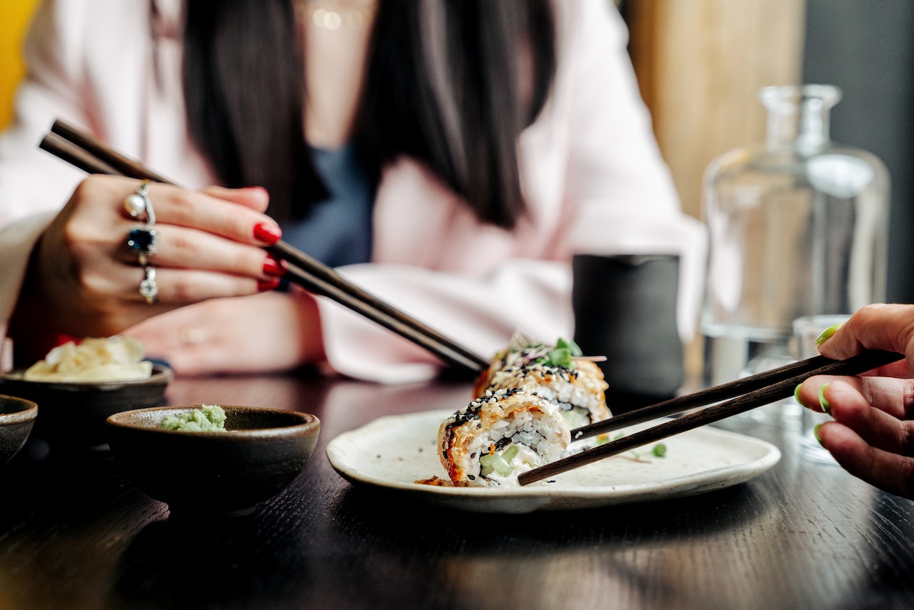 Person holding chopsticks is eating a sushi.