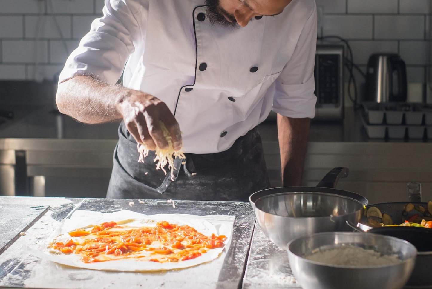 A man is making pizza in the kitchen.