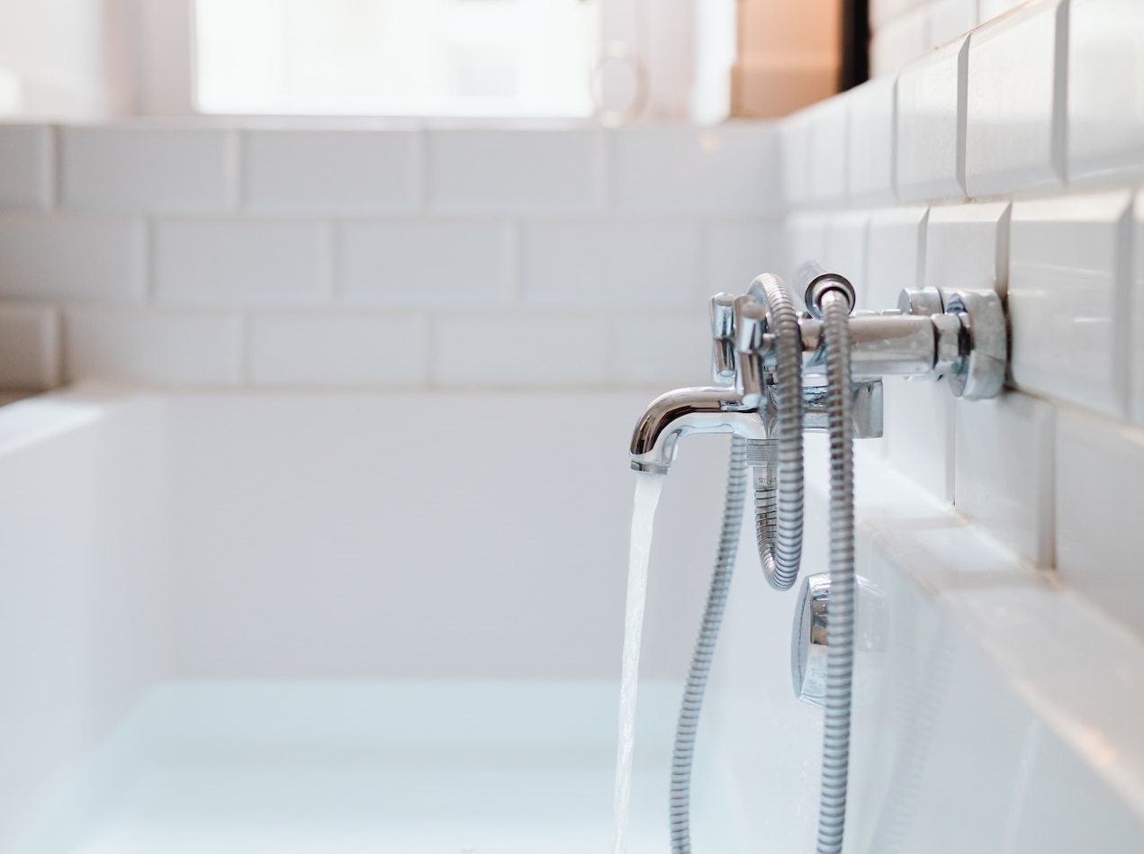 Faucet running water in a white bathtub.