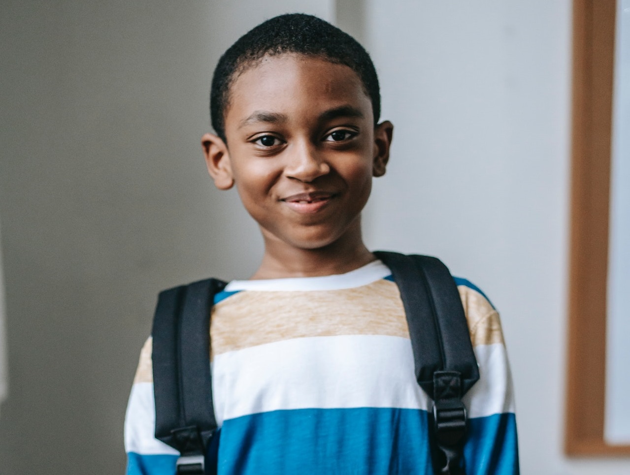 Small black kid in sweater is smiling.