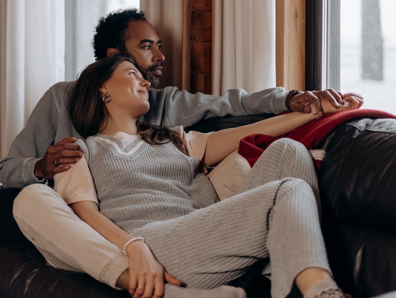 Couple in grey clothes are seating on the sofa.