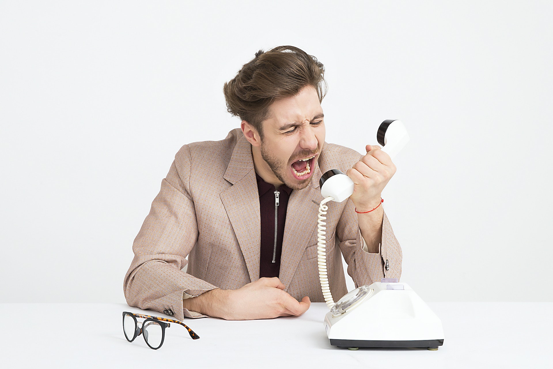Angry man yelling on the phone wearing brown jacket