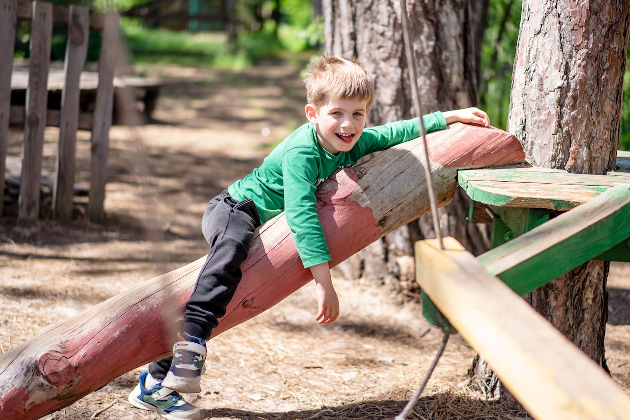 Boy in green sweater is playing in the park.