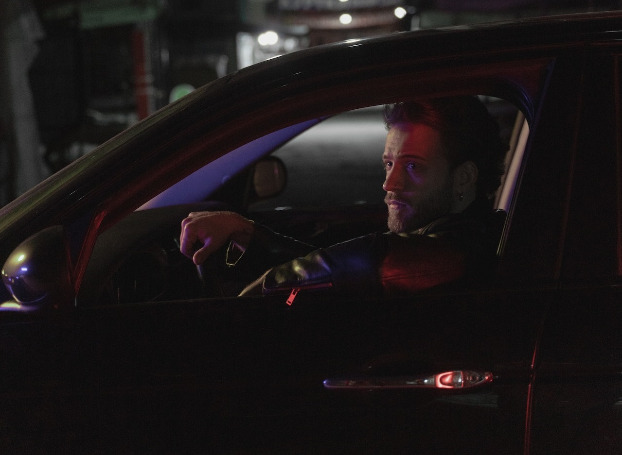 Man is seating in his car at night.