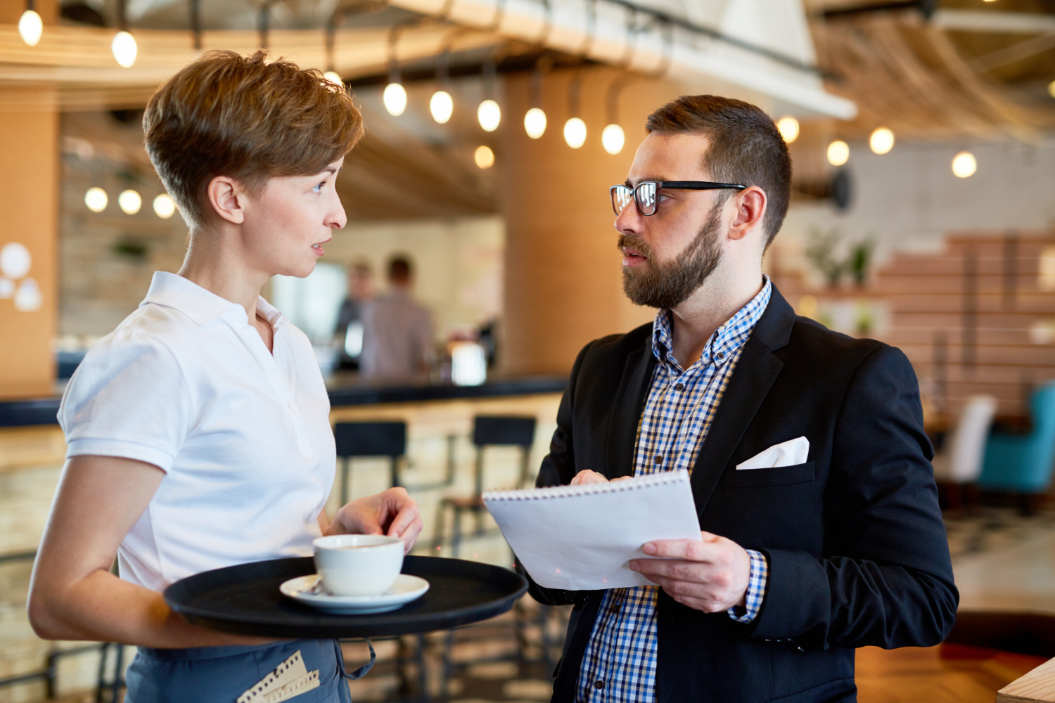 Waitress is talking with a man in restaurant.
