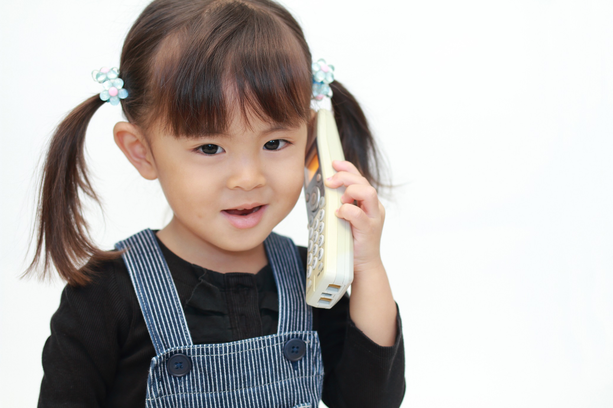 Small girl is talking on the cordless phone.