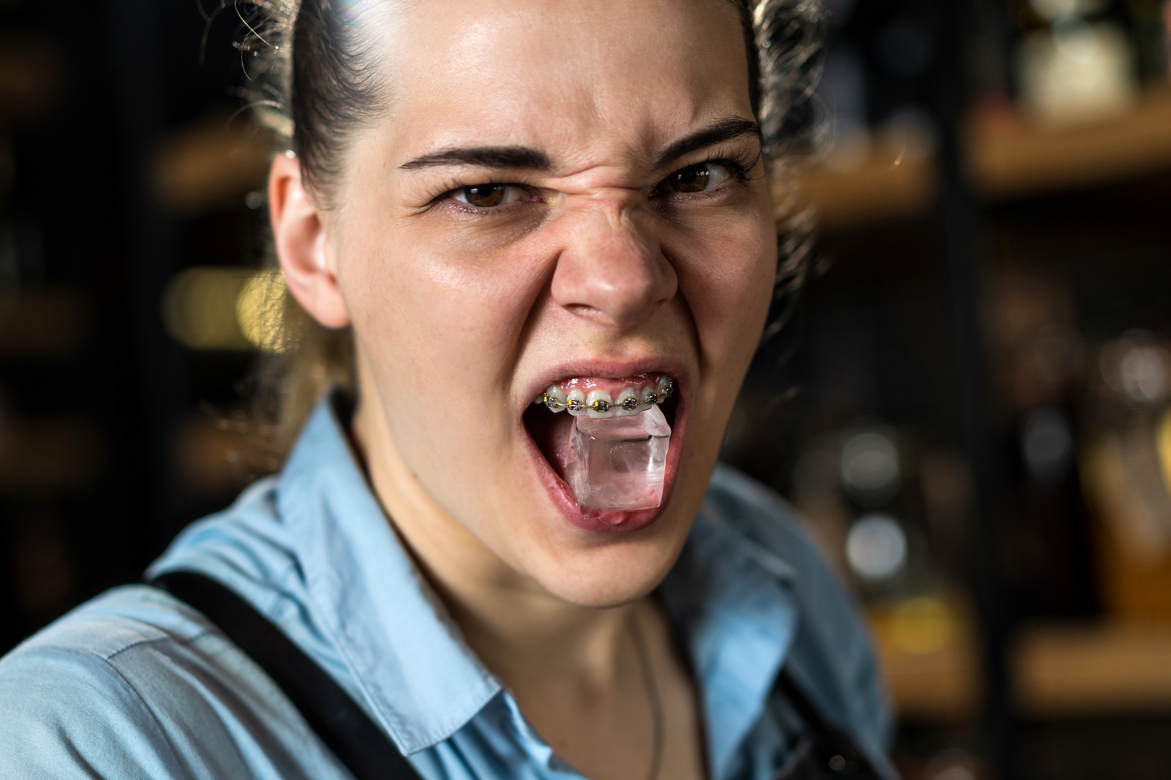 Woman is holding ice cube with her teeth.