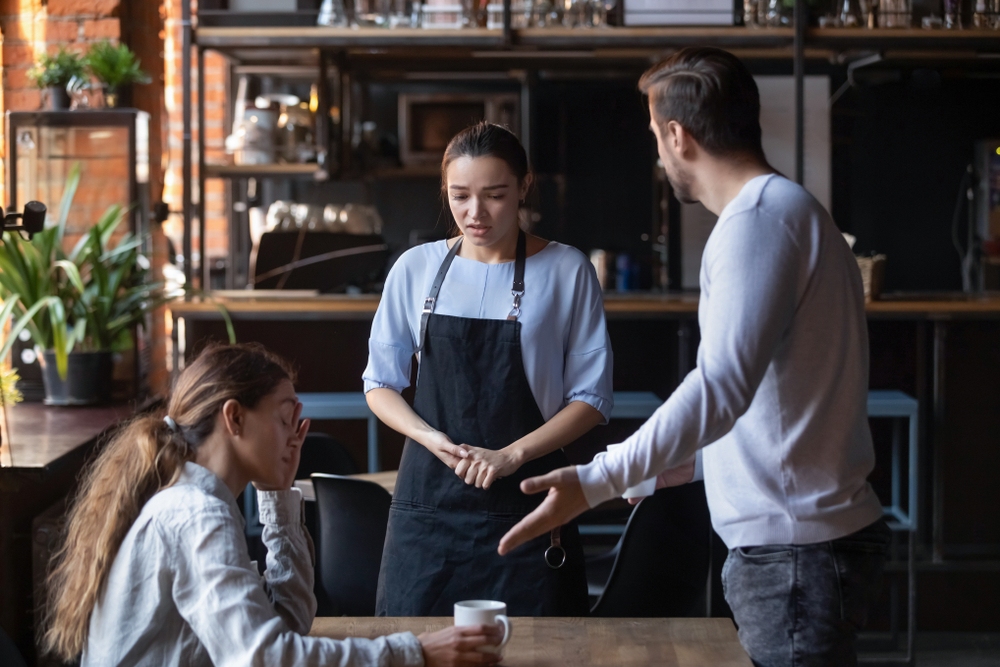 Angry couple in blue clothes at a waitress at restaurant