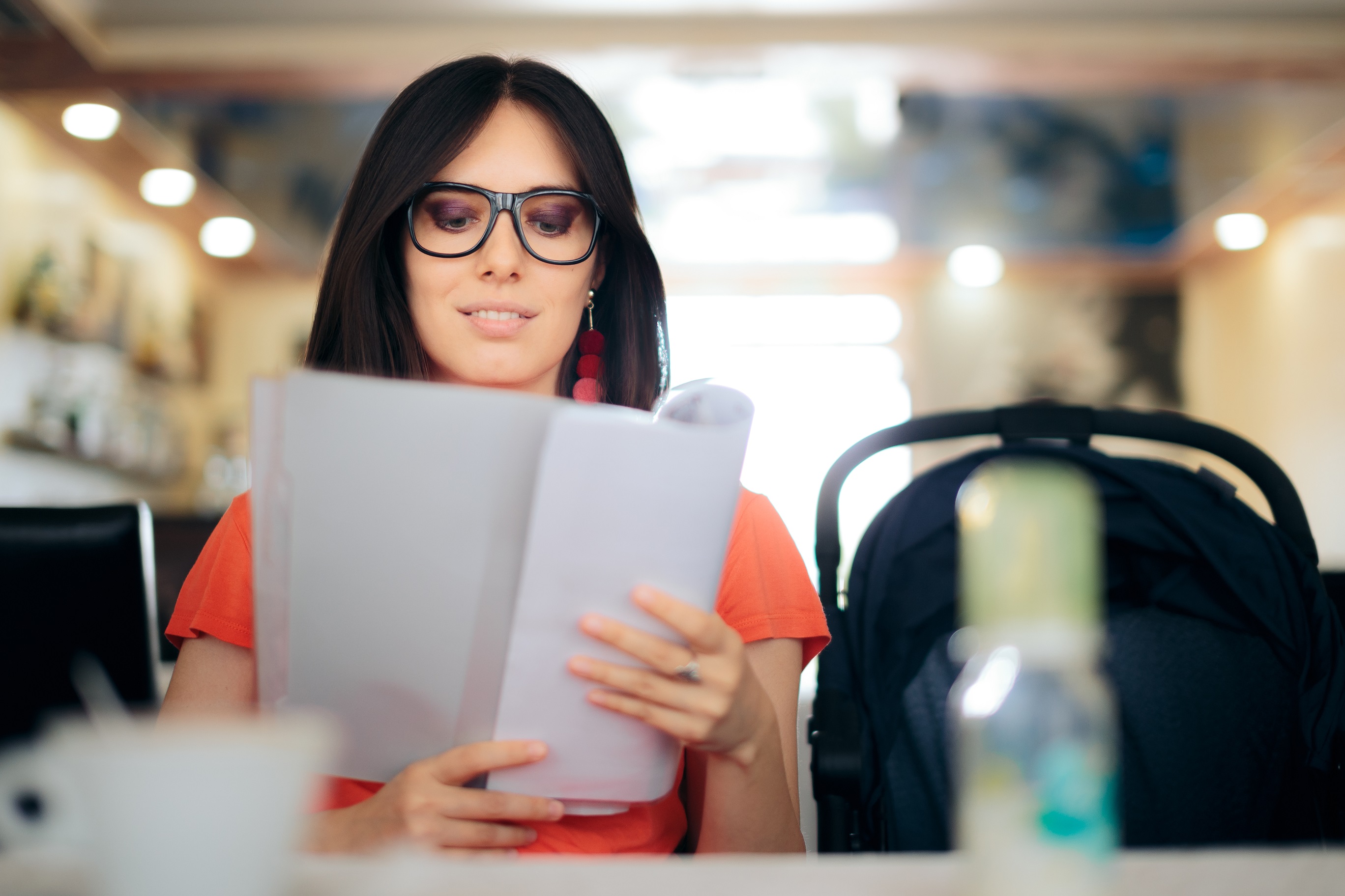 Young woman looking at menu in restaurant with stroller by her side.