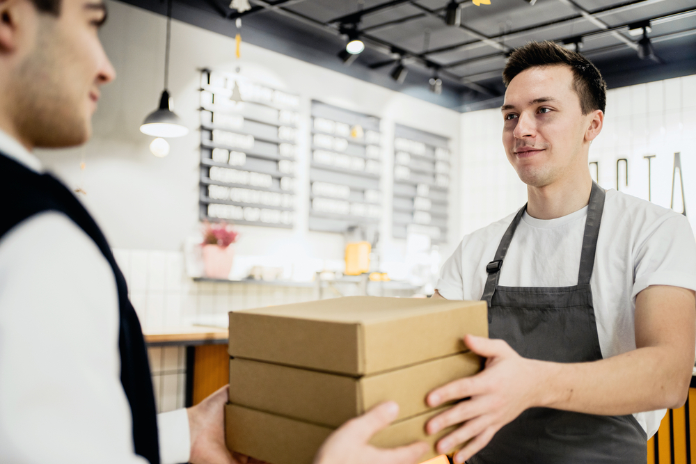 a young male employee in an apron gives order to customer