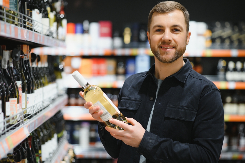 Young man looking at bottle of wine in supermarket