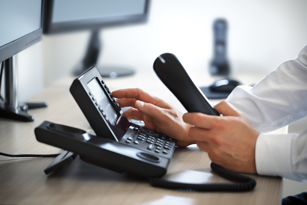 Man Dialing telephone keypad in blue shirt