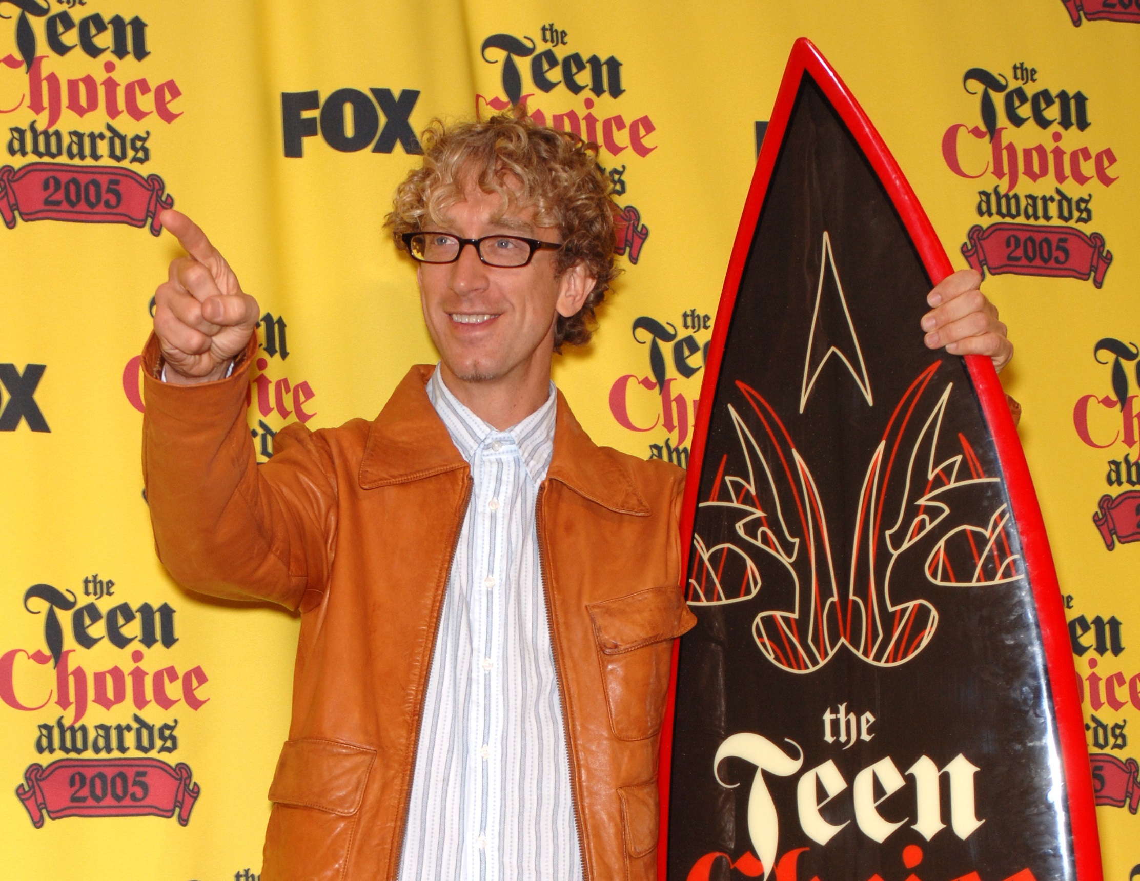 Andy Dick wearing white shirt and brown leather jacket is pointing and looking at side - 2005