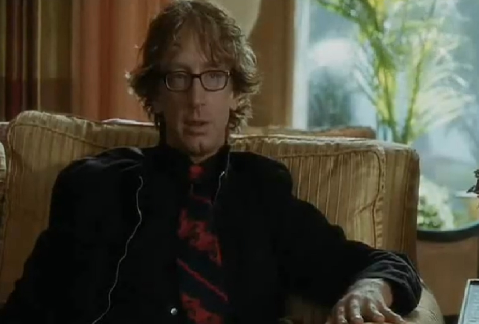Screenshot: Andy Dick is seating and talking to camera - from Funny People (2009)