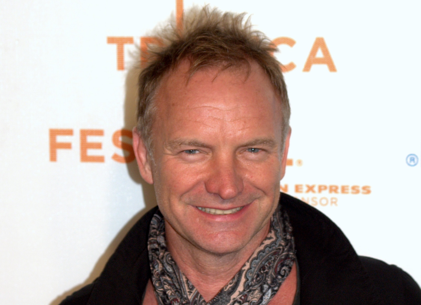 Sting wearing black jacket and grey bandana is looking and smiling at camera - 2009