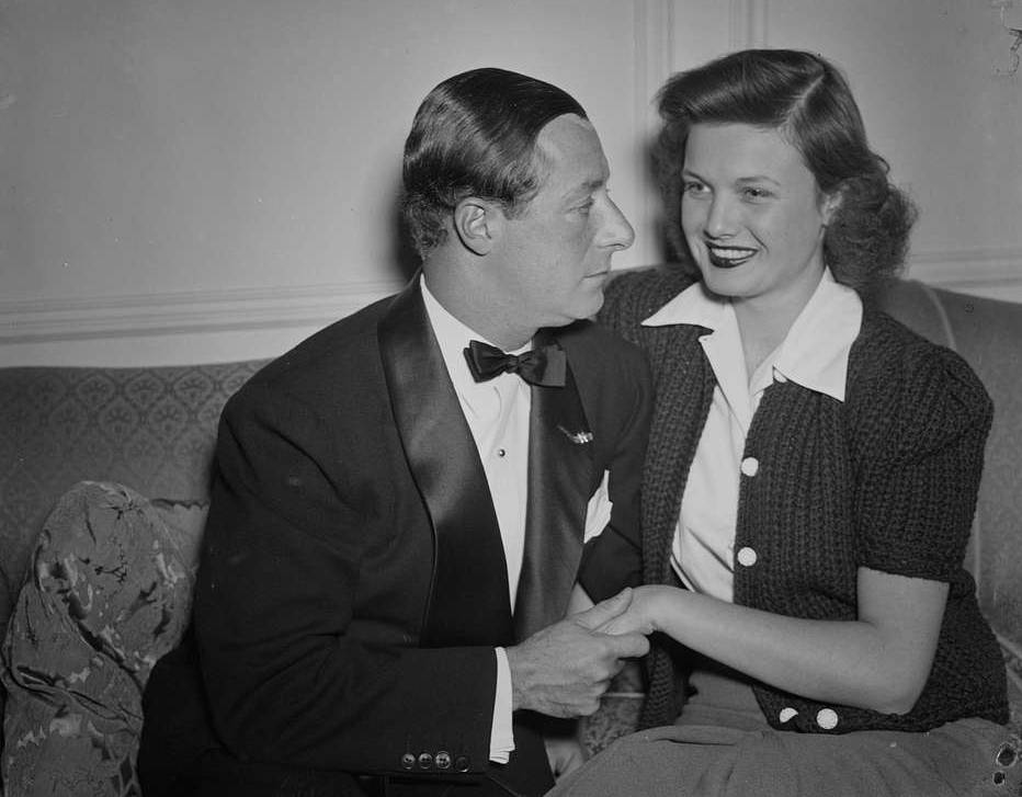 George Jessel and wife, Lois Andrews, seated on the couch