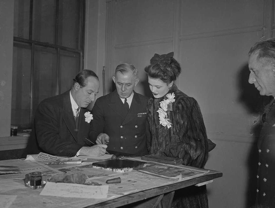 George Jessel and wife, Lois Andrews, with a uniformed officer