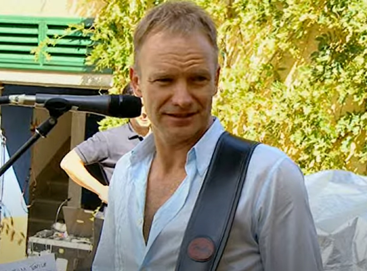 Screenshot: Sting holding a guitar and looking at side - from Sting-All This Time (2001)