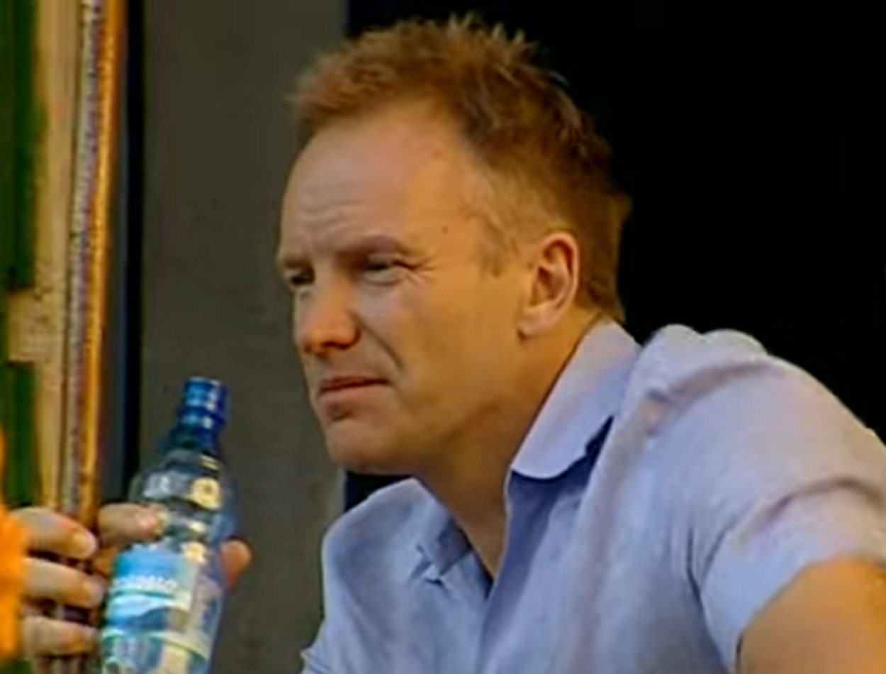 Screenshot: Sting holding bottle of water ,looking at side - from Sting-All This Time (2001)