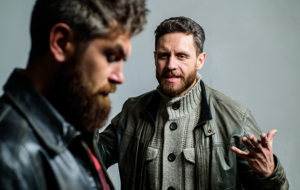 Two male friends in jackets arguing