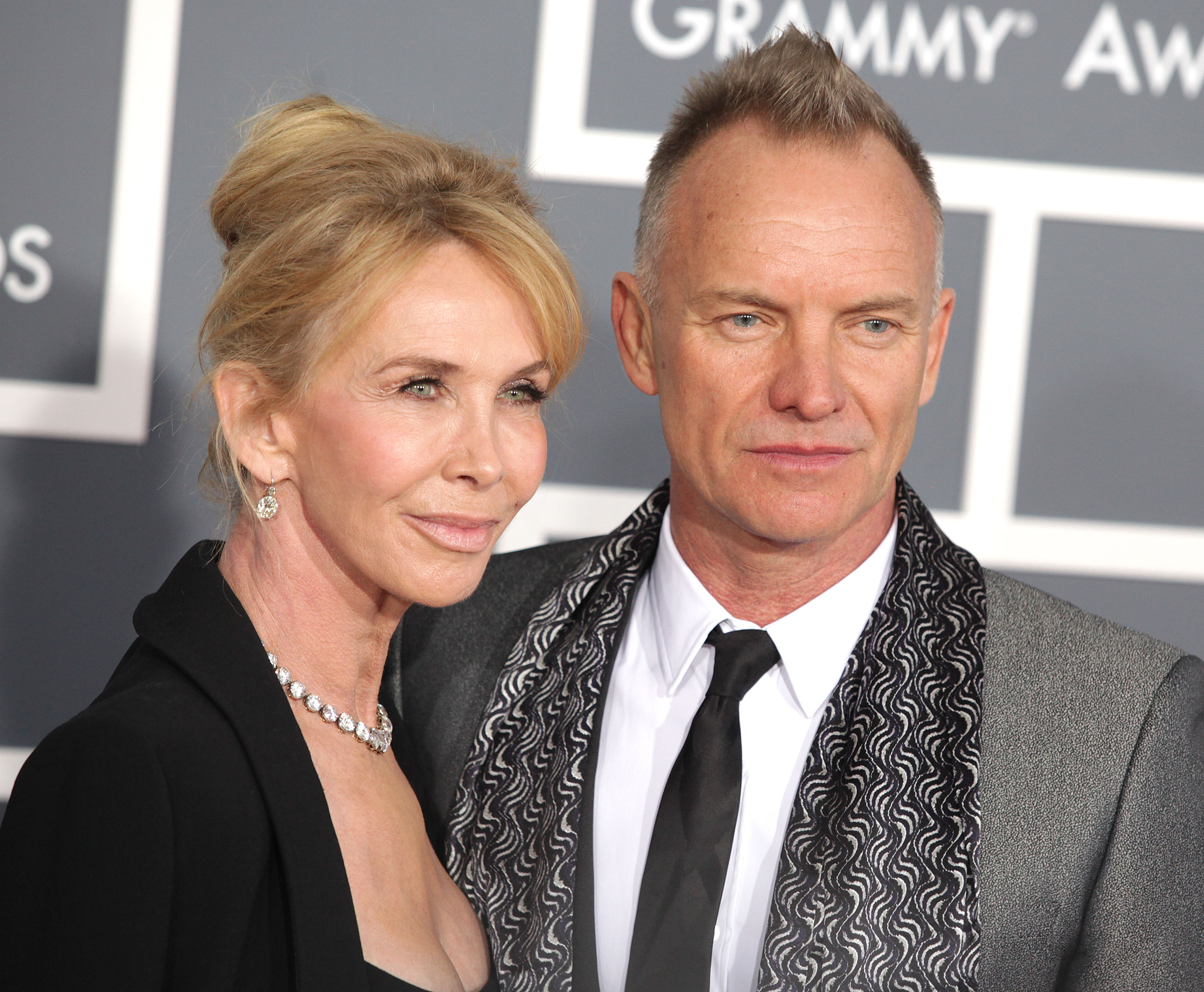 Sting in grey suit & Trudie Styler in black dress are looking and smiling to camera - 2013