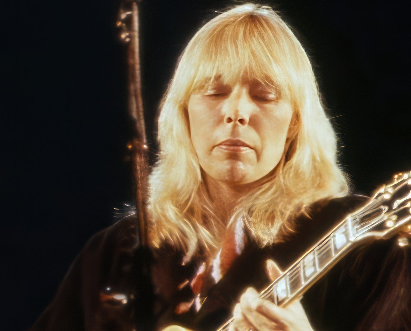 Mitchell performing in 1983 in black clothes playing