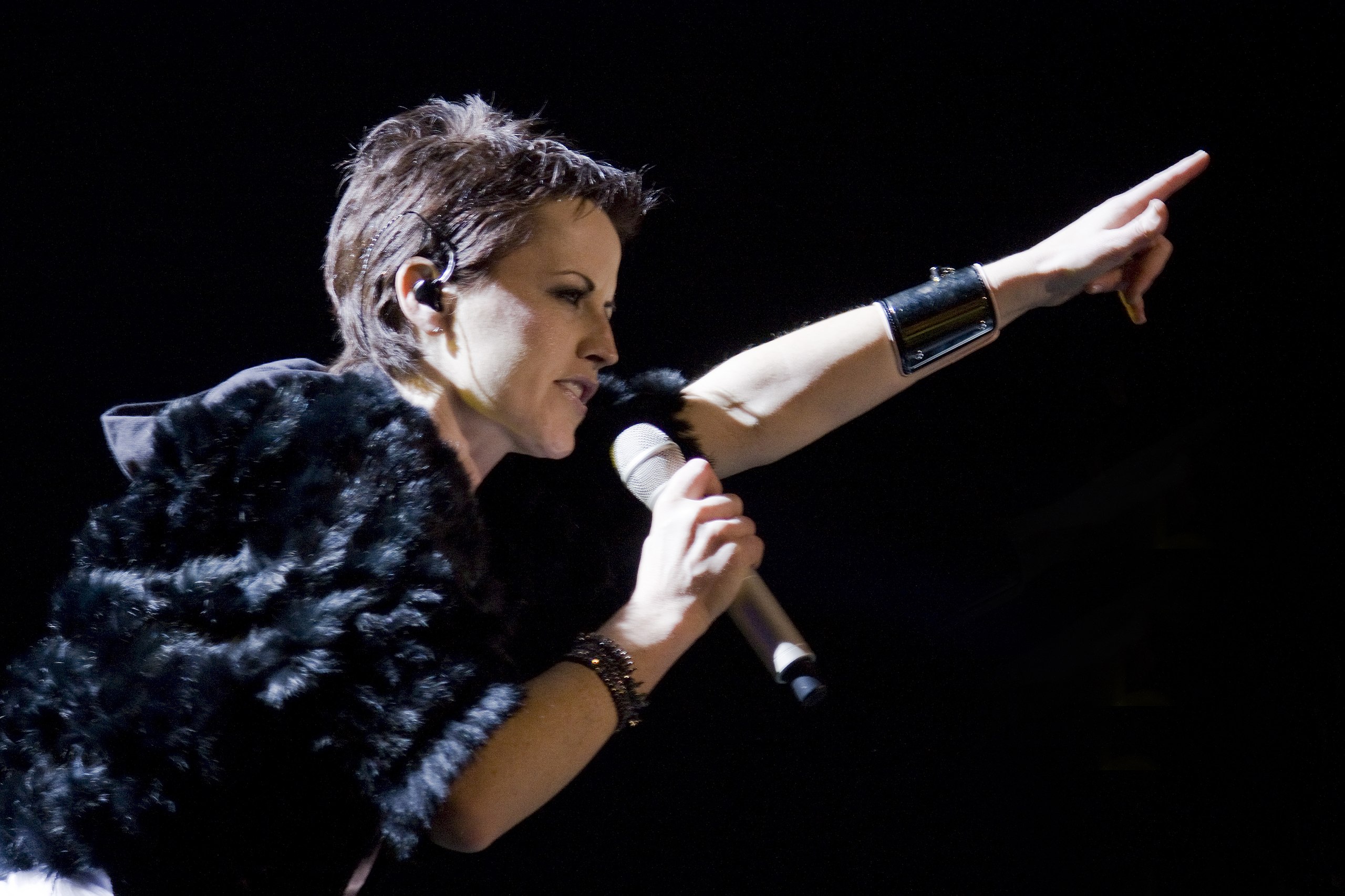 Dolores O'Riordan is performing live on stage pointing up with her arm - 2010
