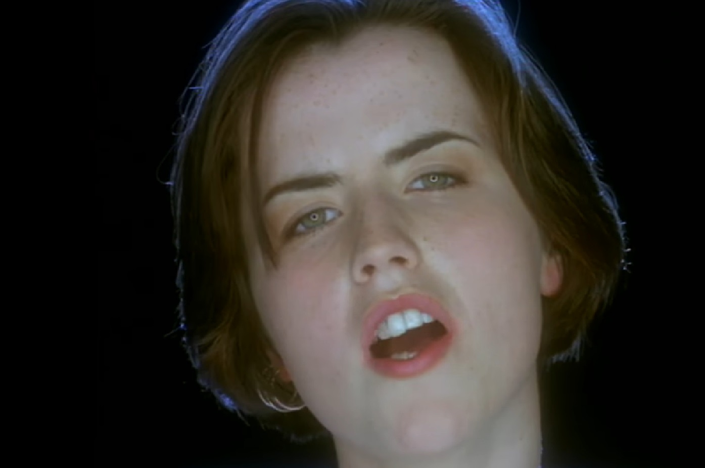 Screenshot: Dolores O'Riordan looking at camera and singing - from Dolores (TV documentary,2018)