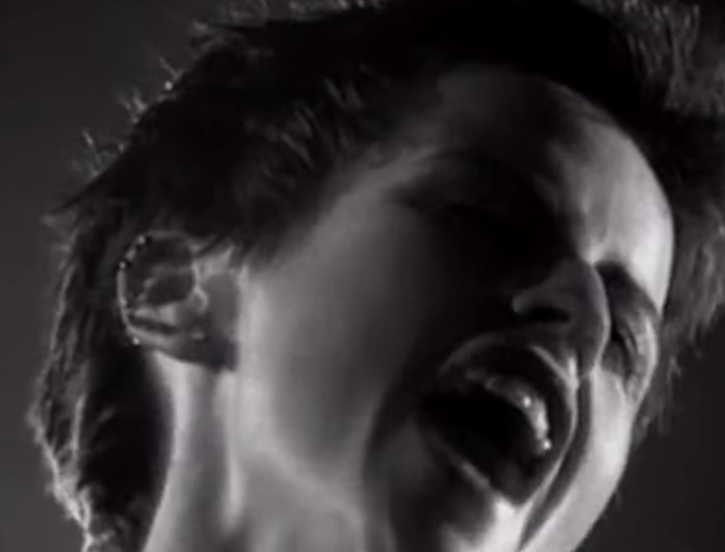 B&W Screenshot: Dolores O'Riordan singing with her eyes closed (close up) - from Dolores (TV documentary,2018)