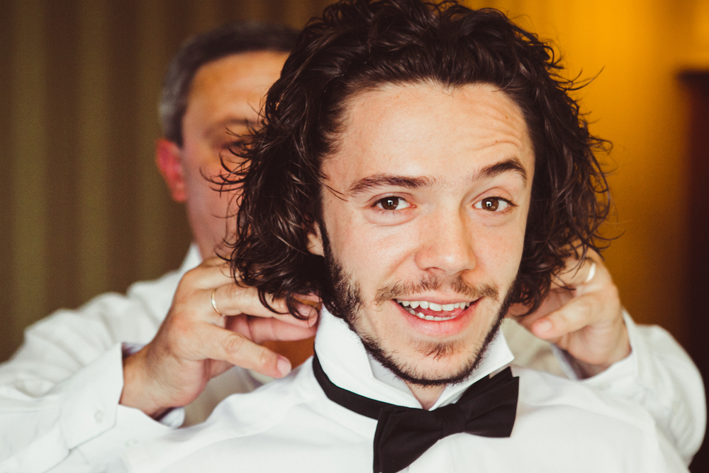 Groom's father helping the groom to get ready for wedding