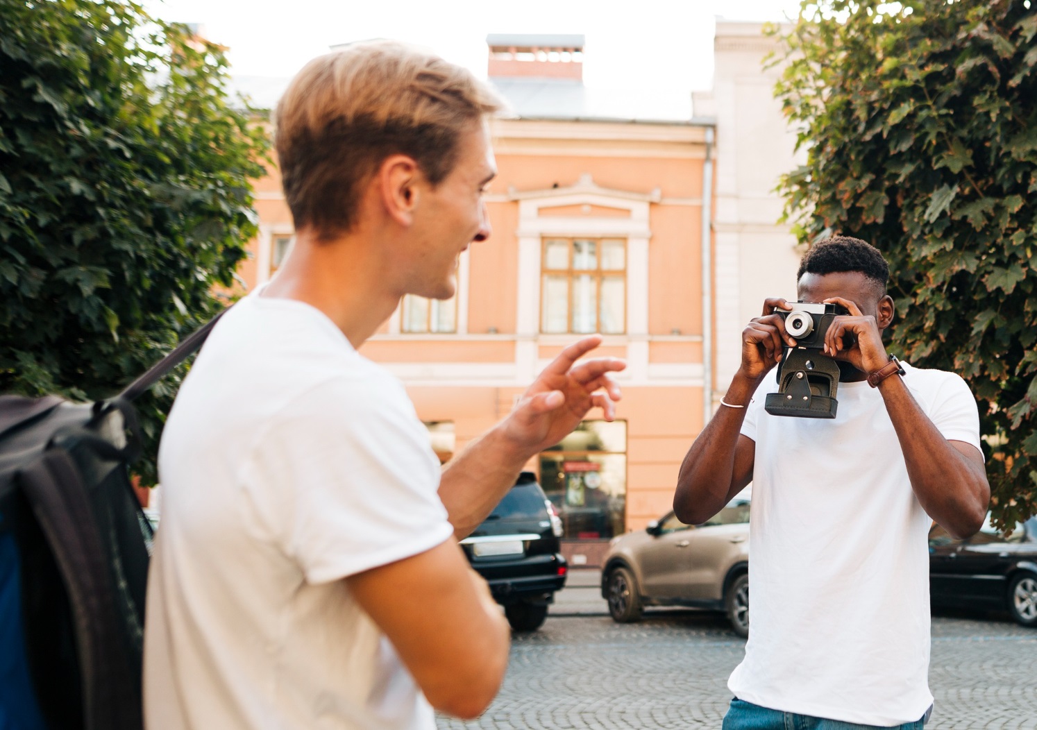 Two man are taking photos outside with camera.