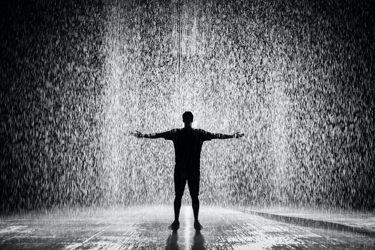 Man standing on the rain at night.