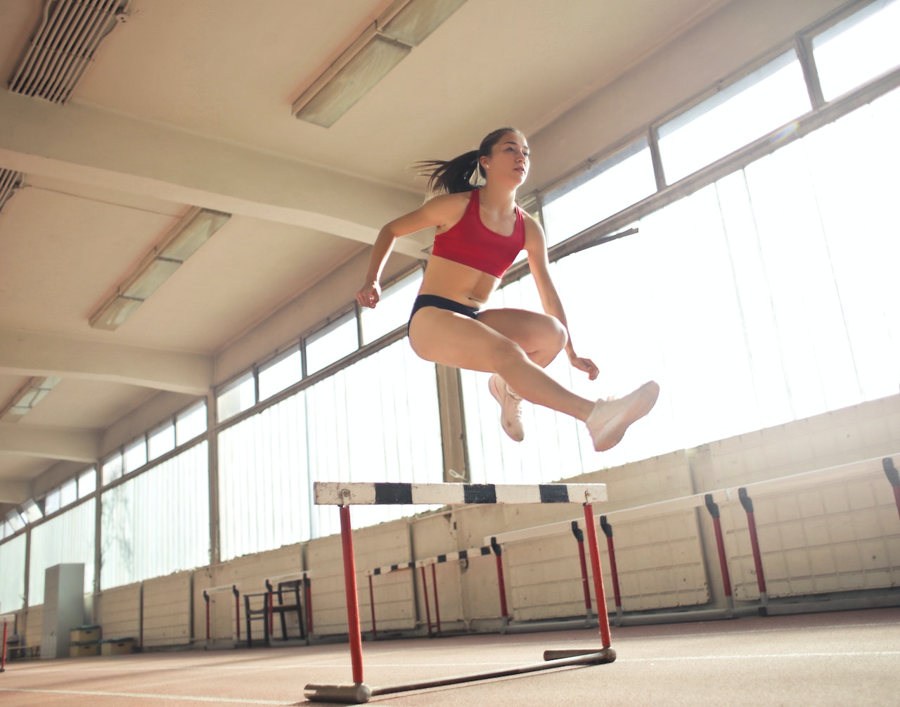Woman jumping on an obstacle on the track.